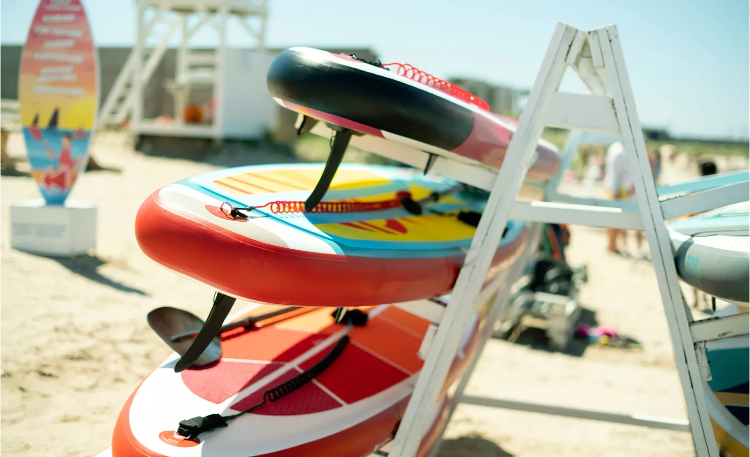 colorful surfboards stacked in a rack outside a beach hire shop.webp