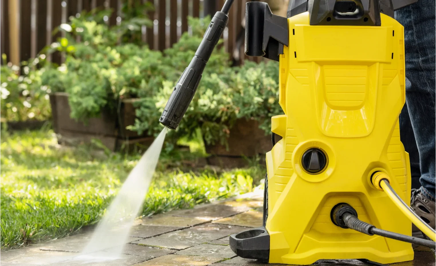 a pressure washer cleaning a concrete driveway.webp