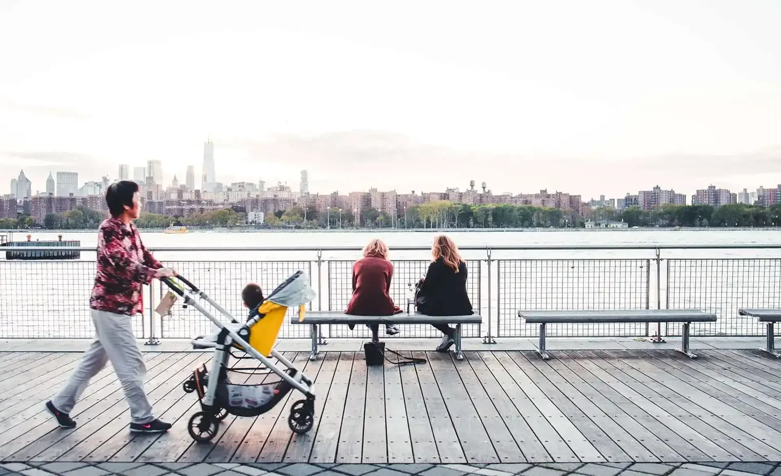 a woman pushing a stroller with a small child on a city bridge.webp