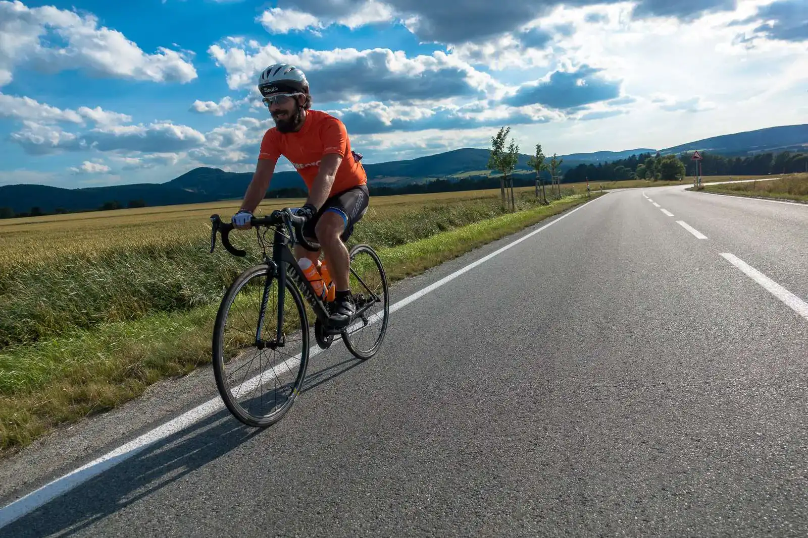 Homem a cavalgar para o pôr-do-sol na sua bicicleta de alto desempenho